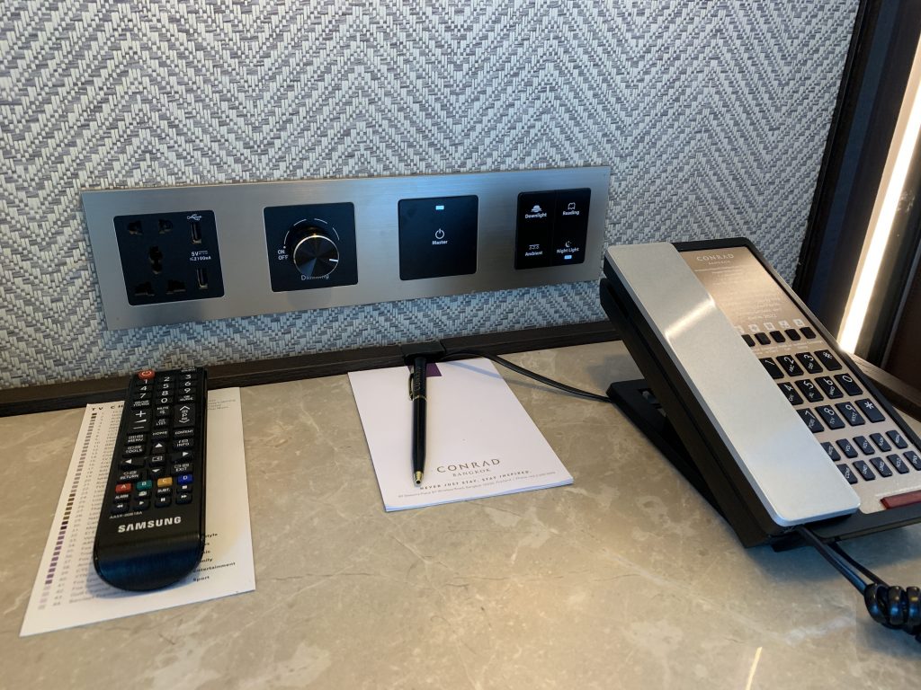 曼谷港麗酒店-工作檯有搖控和電話，以及燈掣插座