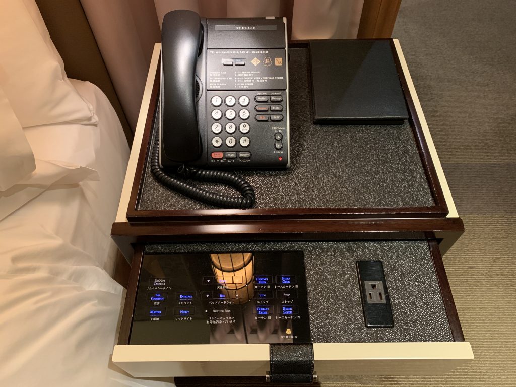 大阪瑞吉酒店-電話，而將床邊桌抽屜拉出，可見到插座及可控制窗簾收合、調節燈光明亮度等的觸控式面板