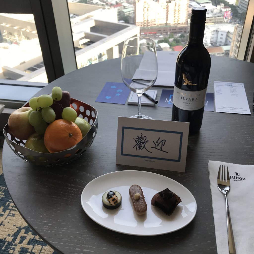 台北新板希爾頓酒店-房間書桌有酒店送贈的紅酒、水果盤和迎賓甜點