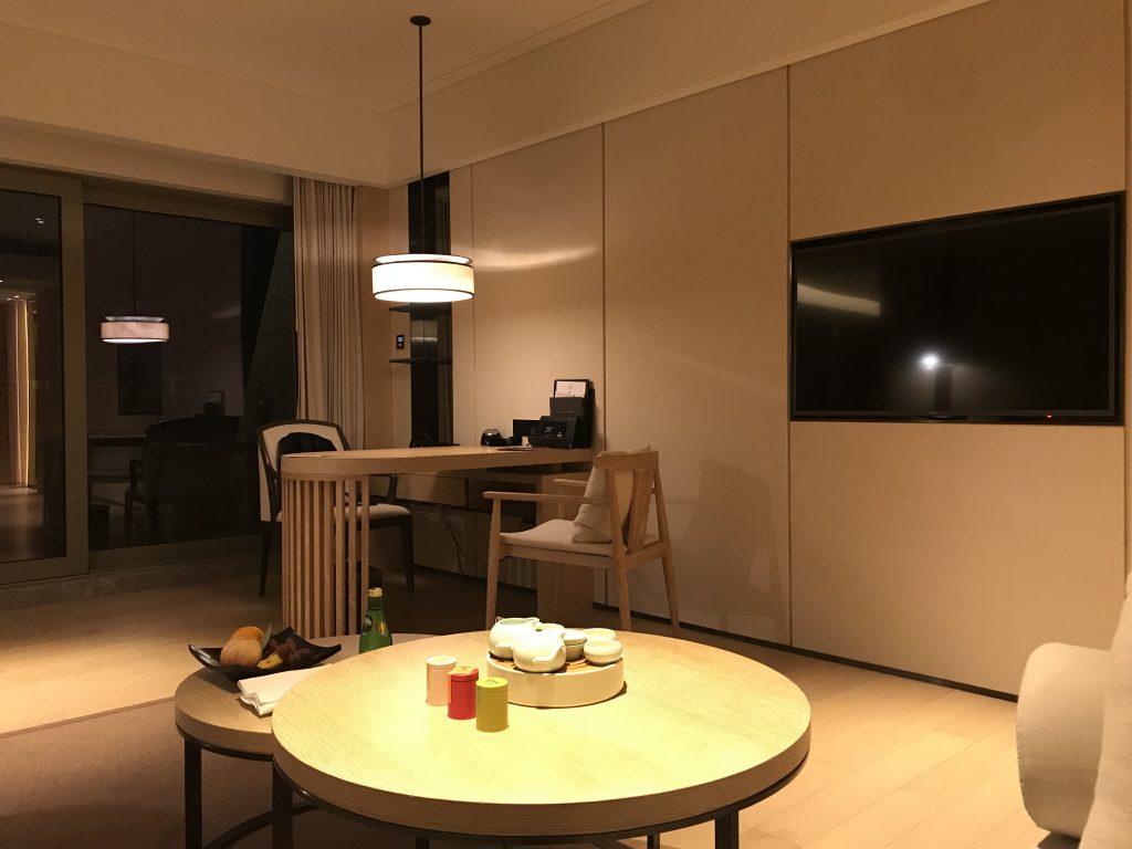深圳蛇口希爾頓南海酒店-客廳桌子有三盒額外收費的茶葉和沖茶工具，而對面是書桌和電視
