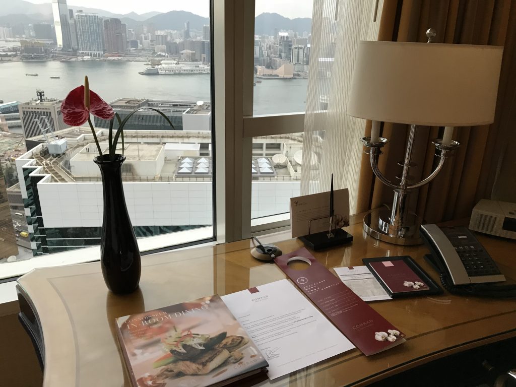 香港港麗酒店-房間書桌上有各式酒店設施小冊子、原子筆、檯燈及電話